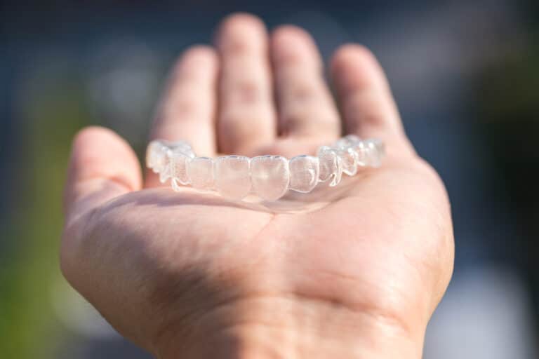 Holding,Invisalign,Braces,On,Bokeh,Background