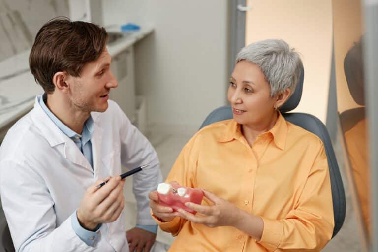 Side,View,Portrait,Of,Smiling,Male,Dentist,Talking,To,Senior