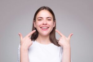 smiling woman who is pointing toward her smile with both hands